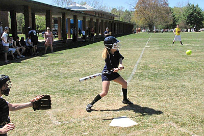 A girl swinging at a pitch during a softball game.