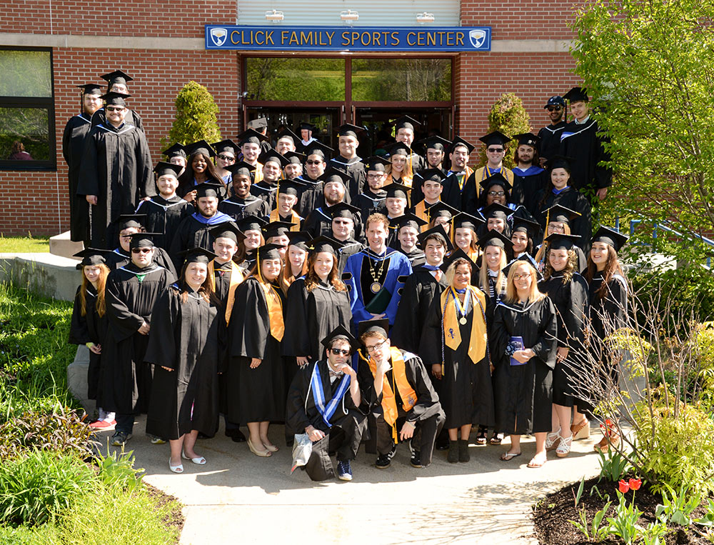 Graduates pose outside Click Center in caps and gowns