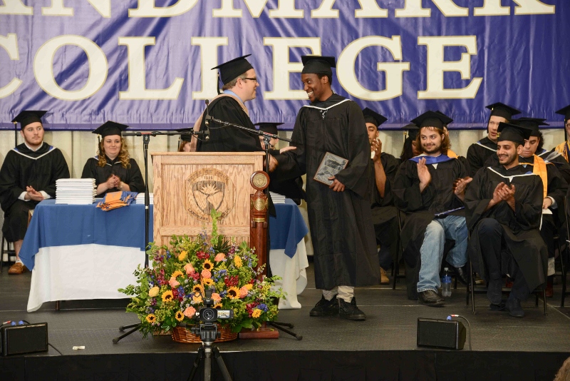 Marc Thurman on stage at graduation receiving award from Michael Luciani