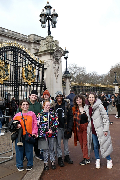 Seven students pose for a photo in front of a large gate