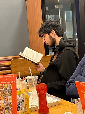 Picture of student at table reading a book