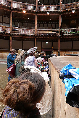 Students standing next to the stage inside globe theater, which is eye level in height