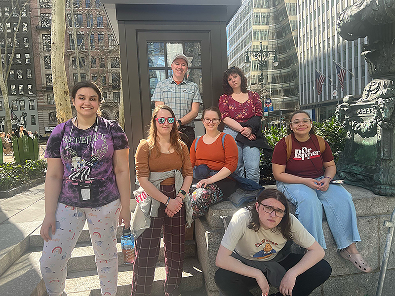 Seven people posing for a photo outside in New York city