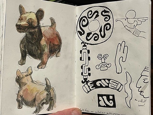 Sketch pad with drawings of small dog from front and back on left page and then several Egyptian symbols on right page