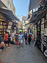 Narrow street with artists' paintings on both sides