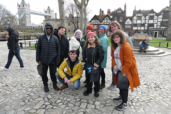 Nine students pose for a photo on cobblestone street