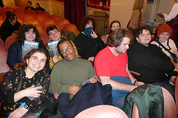 Students seated in two rows of theater seats, smiling for camera