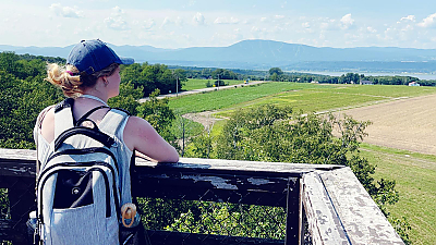 student observing beautiful view of farmlands, river, and mountains