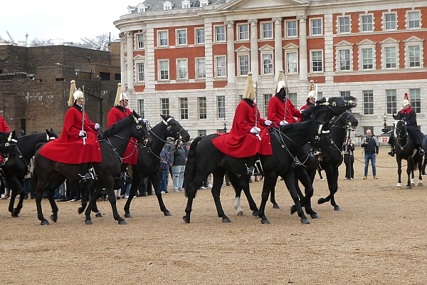 Picture of several men on horseback wearing ceremonial red robes and gold helmets