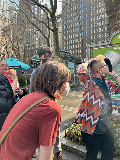 Four students outside in New York looking away from the camera near a public map labeled Bryant Park.