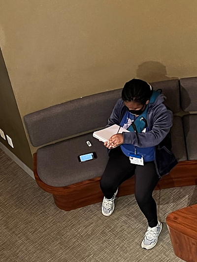 Overhead shot of female student drawing while seated on padded bench