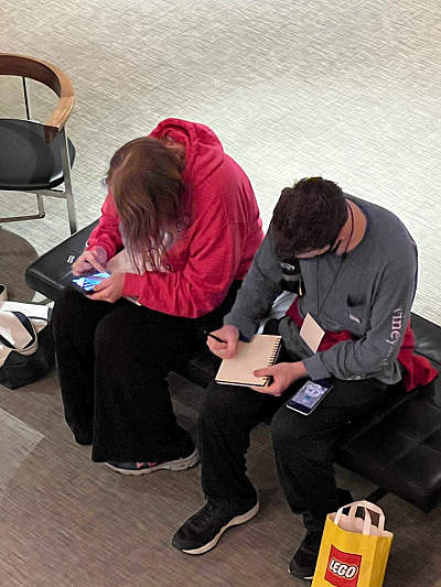 Overhead shot of two students sketching while seated on padded bench