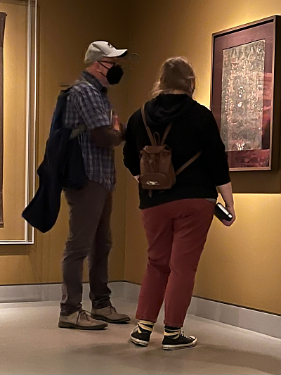 Image of male professor and female student looking at artwork on museum wall