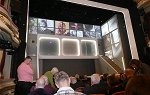 Audience view of stage set, which features images on multiple video screens and staircase leading up the right-hand side. 