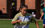 Carolyn Hendry kicking soccer ball on quad