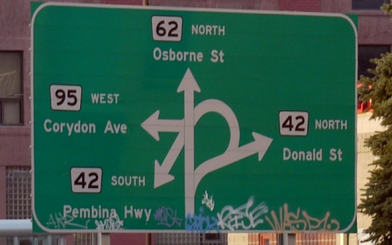 The famous 'Confusion Corner' street sign which shows four overlapping arrows each pointing to how to navigate to a different road