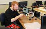 A student in a computer lab working on a Lego robot. 