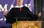 Thumbnail image of John Elder Robison making remarks at the Fall 2019 convocation ceremony. He is wearing the traditional black robes and his arms are stretched wide as he makes a point. 