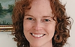 Picture of Lynne Shea facing camera and smiling. She has red wavy hair and light complexion.