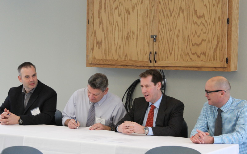 Three superintendents and Landmark College President Peter Eden sit at table while one superintendent signs memorandum of understanding