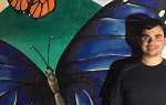 A student stands in front of a mural featuring a monarch butterfly