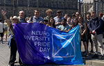 Landmark College Study Abroad group posing for picture outdoors in Amsterdam and holding a large blue flag that says Neurodiversity Pride Day