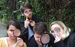 Four students on the Summer 2018 Study Abroad trip to New Zealand look at the camera while holding magnifying glasses to their eye. 