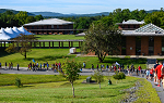 Students walking downhill on a concrete path overlooking a college campus with mountains and green grass in the background