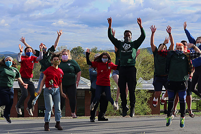 The Centers for Diversity and Inclusion staff outside on the upper quad jumping in the air in a celebratory manner.. 