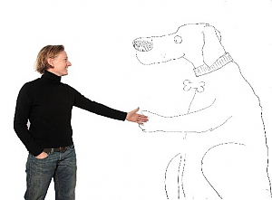 Woman wearing a black turtleneck and jeans extending her left hand out toward a cartoon drawing of a dog, who is extending their left paw out toward her.