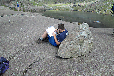 One students leaning against a rock reading 