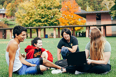  Students sitting on the grass outside of the Student Center in Autumn.