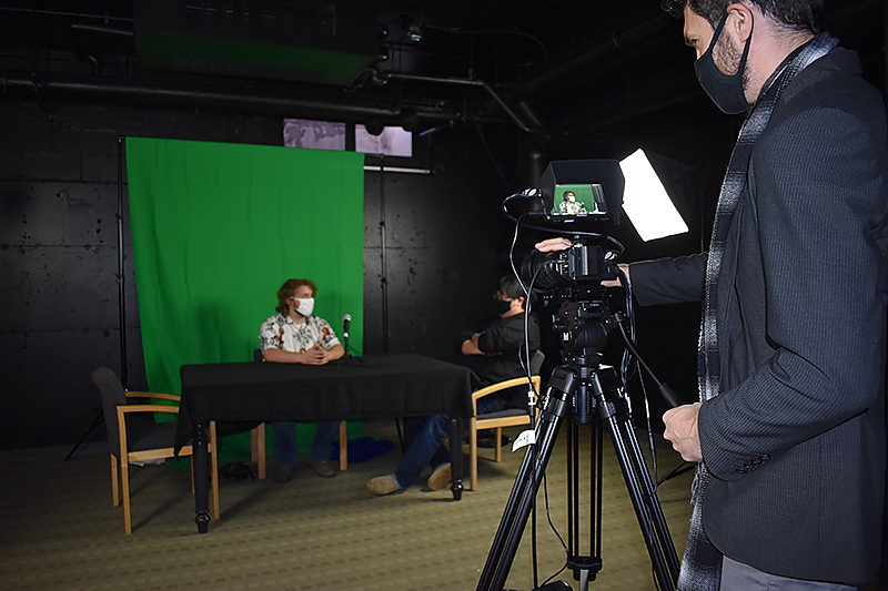 Two students work on a video project in the television studio with faculty member Gyuri Kepes