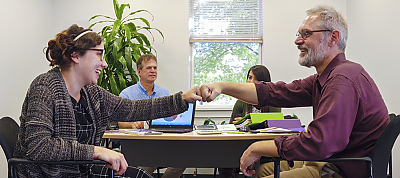Employer fist bumping employee while employees watch