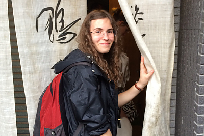 Student Jenny Beller entering building through a curtain in Japan