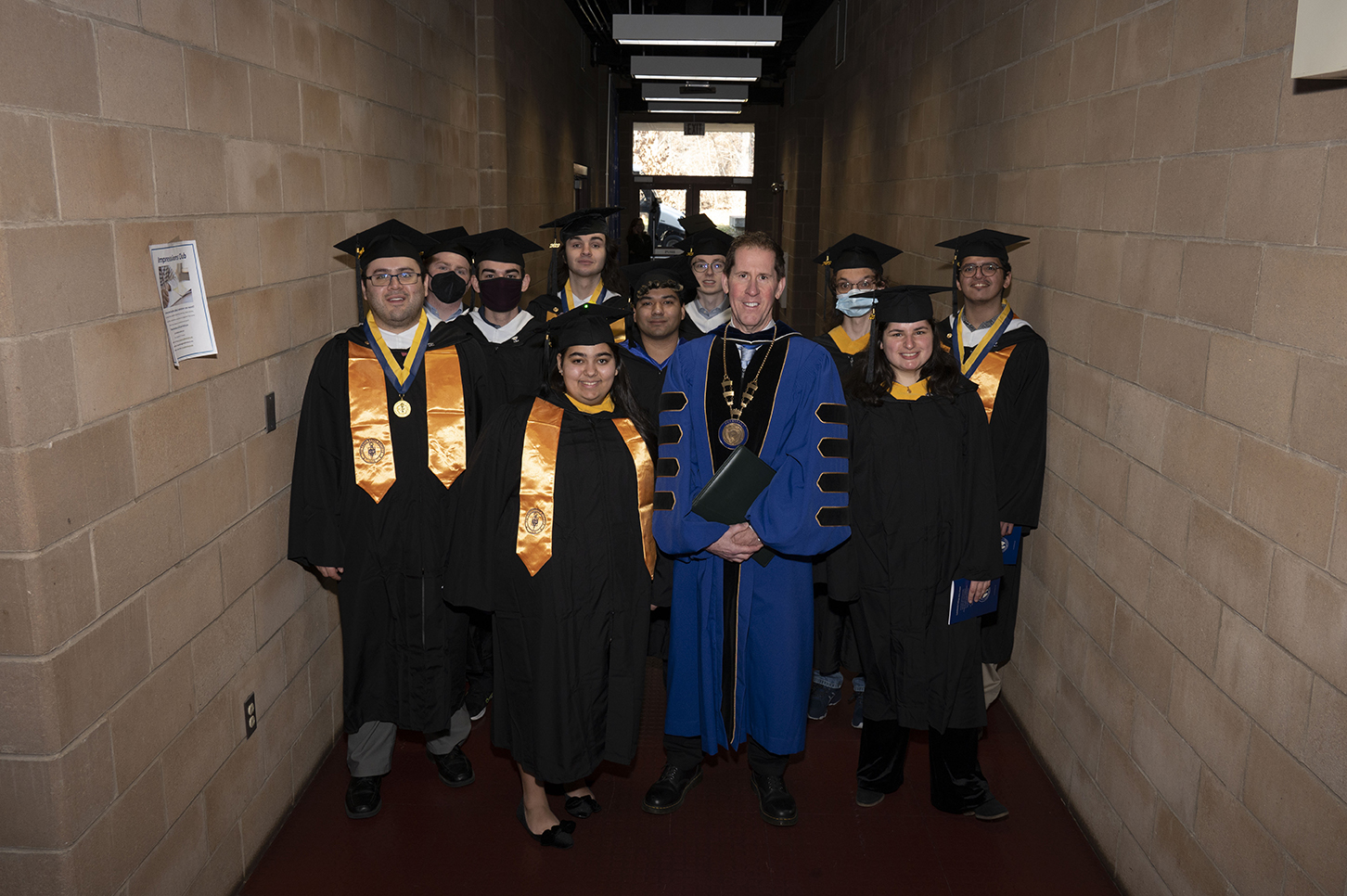 President Eden poses for a photo with a group of students at the December 2023 graduation ceremony