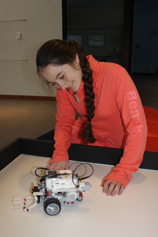 Middle schooler smiles while looking at LEGO robot