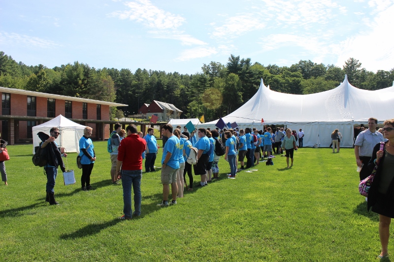 A double line of people waits outside a large tent on the Landmark College quad