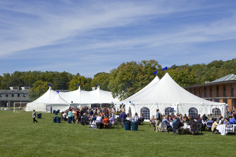 Attendees eat lunch on the quad beside large tents